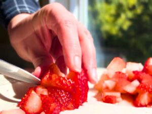 A woman cutting strawberries.