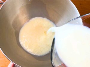 Milk being poured into a metal bowl.