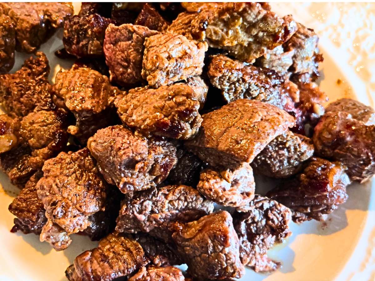 Cooked beef cubes on a white plate.