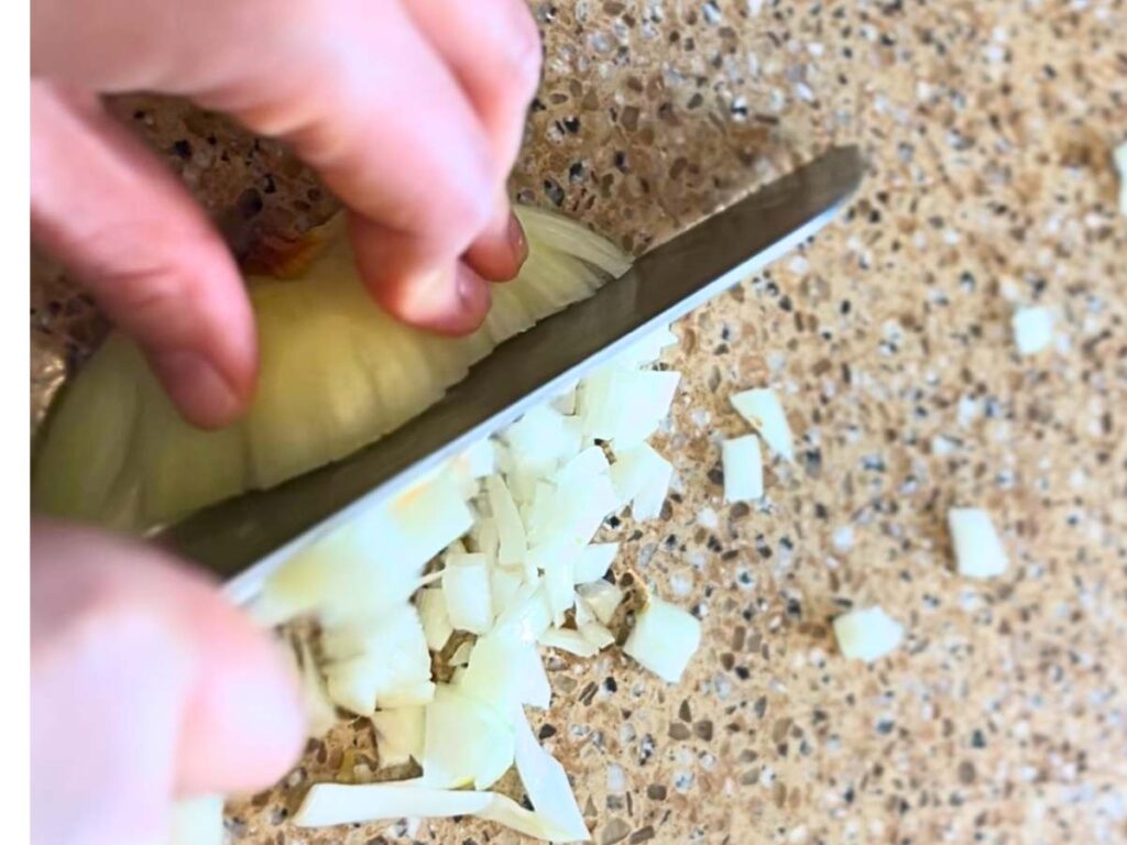 woman cutting onions into a small dice.