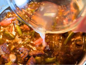 Woman adding lemon juice to a pot of beef stew