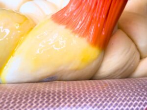 Woman brushing bread dough with an egg wash.