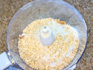 A bowl of a food processor with flour sugar and oats inside.