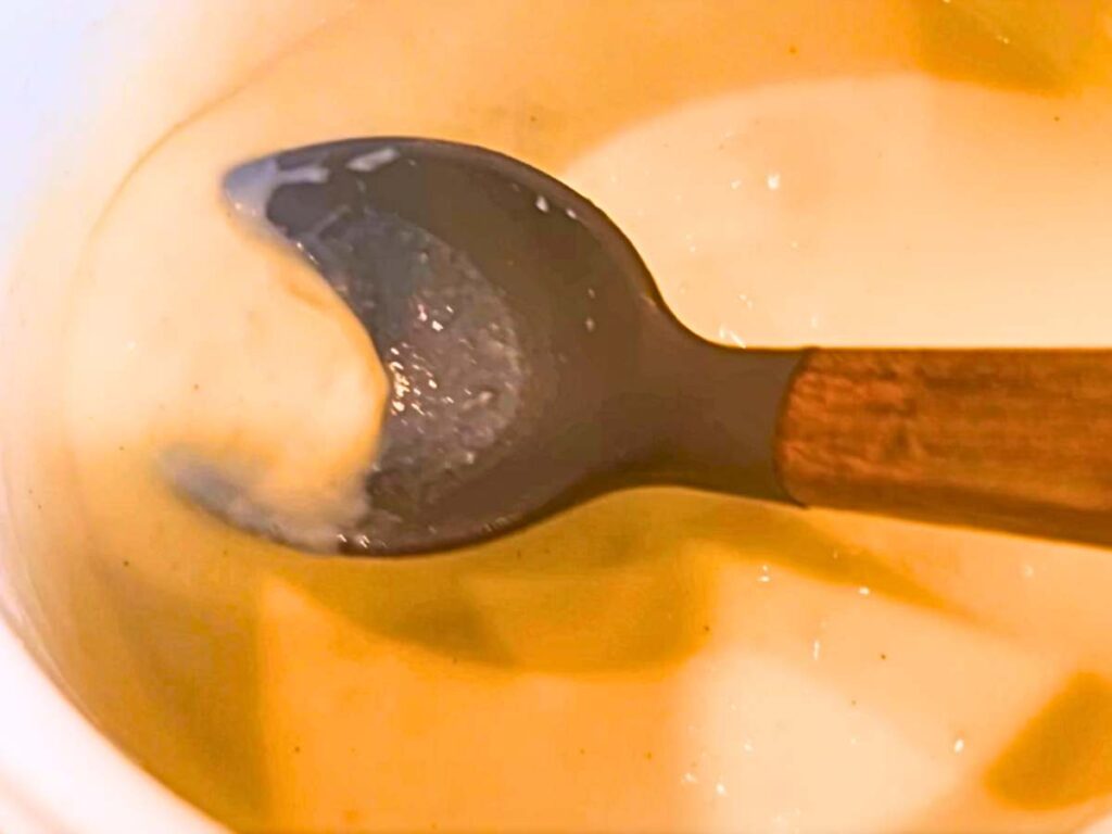 A woman mixing a white sauce in a white sauce pot.