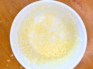 A white round dish dusted on the inside with shredded cheese