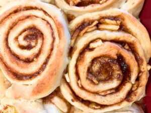 A close up look at baked cinnamon rolls in a red casserole dish.