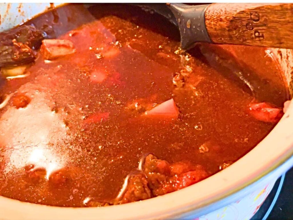 Beef broth added to a pot of beef, vegetables, and paprika