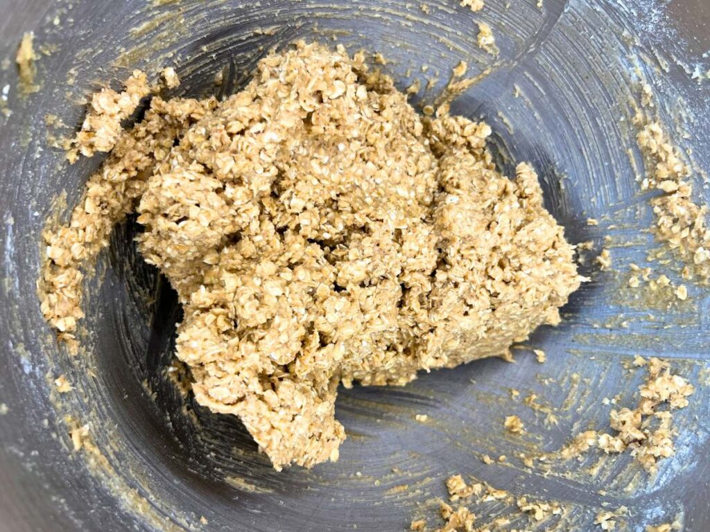 Oatmeal cookie batter in a metal bowl.