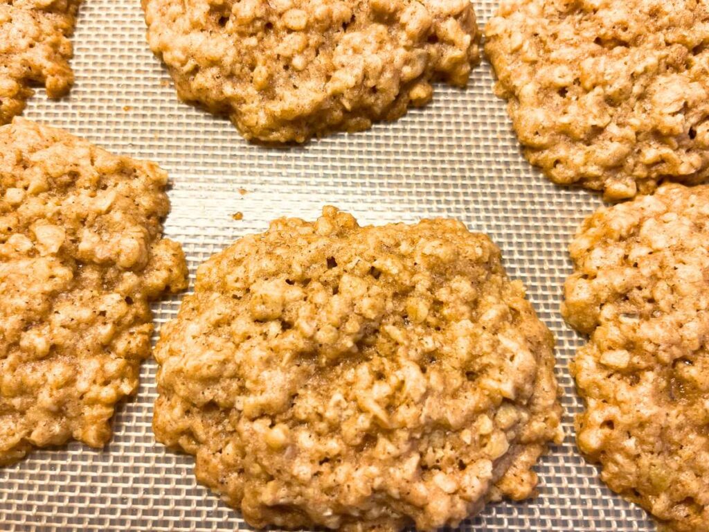 Baked oatmeal cookies on a lined baking sheet.