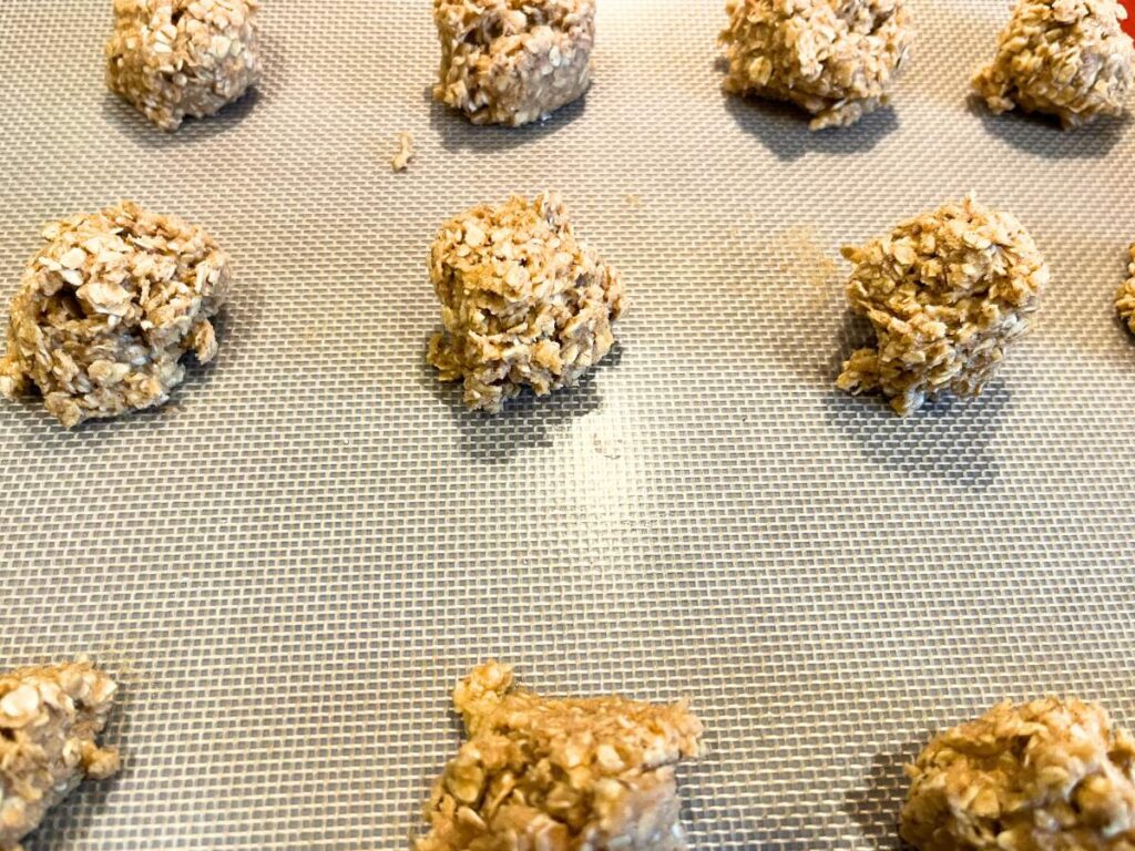 Little mounds of oatmeal cookie batter on a lined baking sheet.