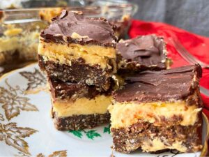 A side view of 4 Nanaimo bars on a gold maple leaf plate.
