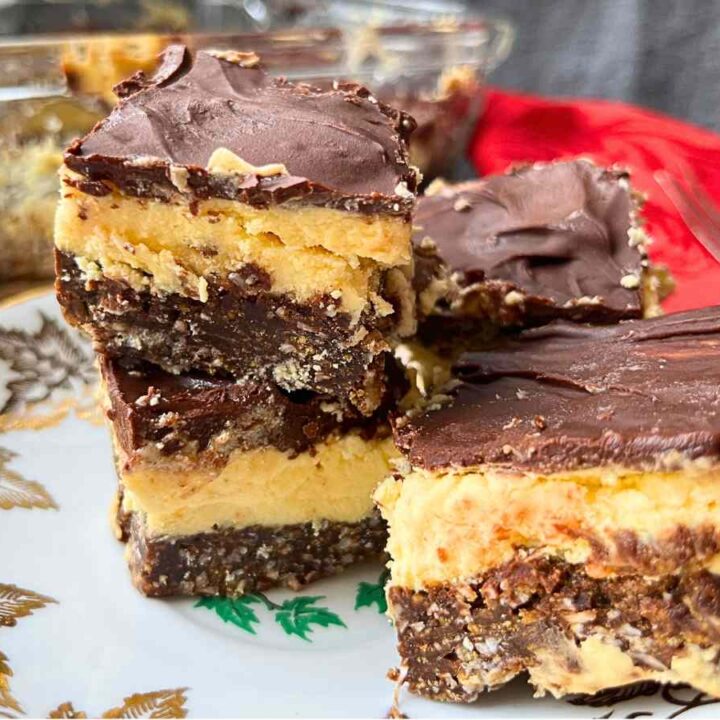 A side view of 4 Nanaimo bars on a gold maple leaf plate.