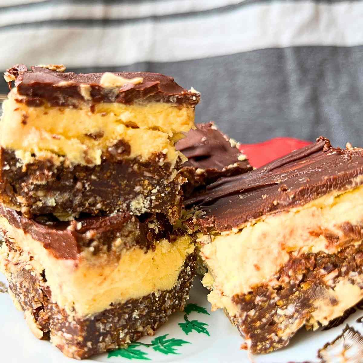 A close up side view of three Nanaimo bars on a gold maple leaf plate.