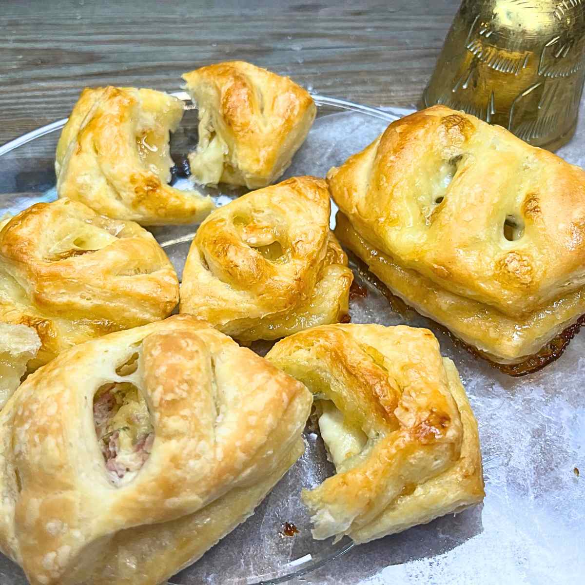 There is a group of puff pastry appeatizers on a glass plate.