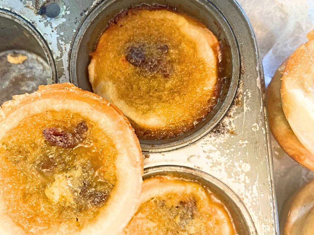 Baked buttertarts in a muffin tray.