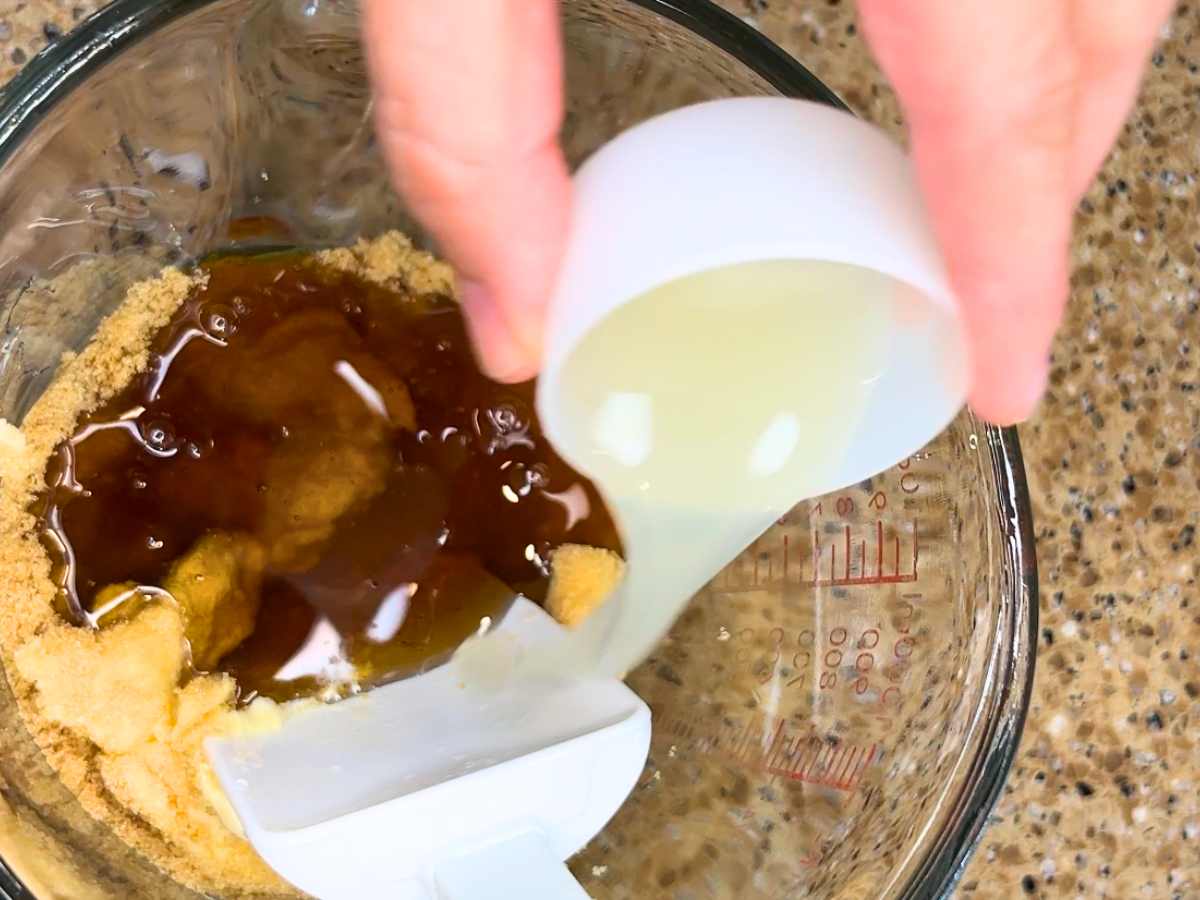 Woman pouring lemon juice into a glass measuring cup.