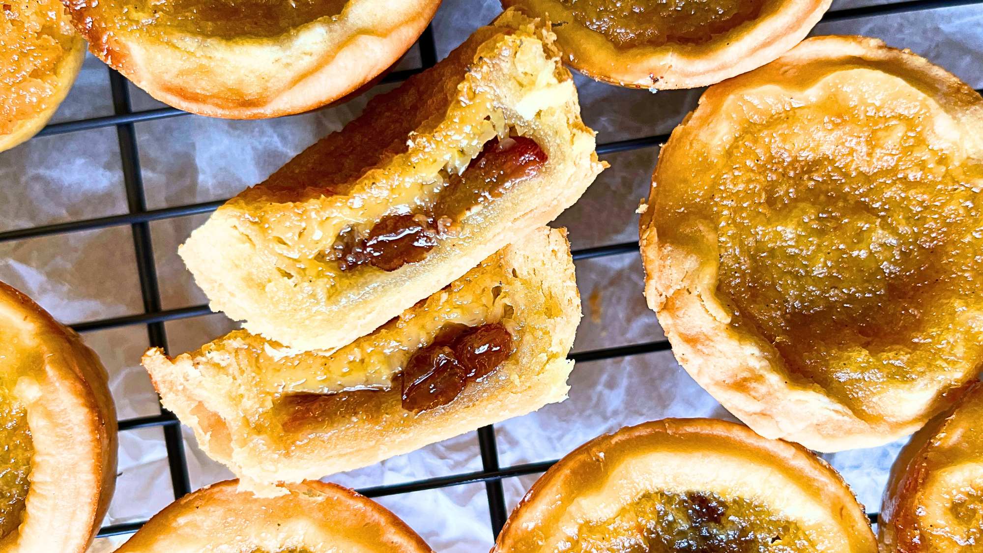 There is a wire rack full of tarts. One is cut in half showing the inside.