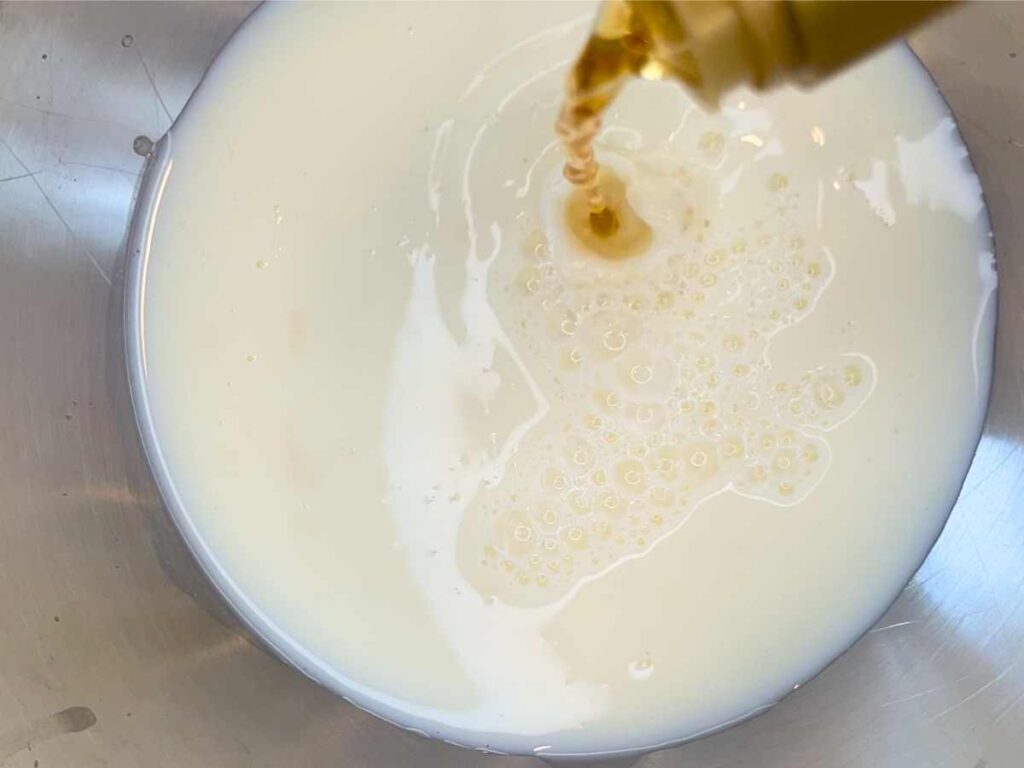 A woman pouring apple cider vinegar into a bowl of milk.