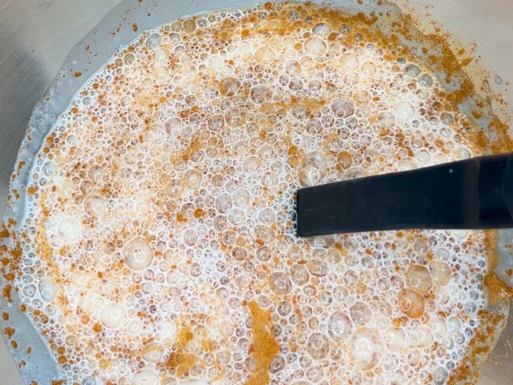 A metal bowl with milk eggs, and cinnamon being mixed inside.