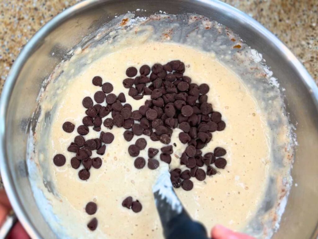 Pancake batter in a metal bowl with chocolate chips on top.