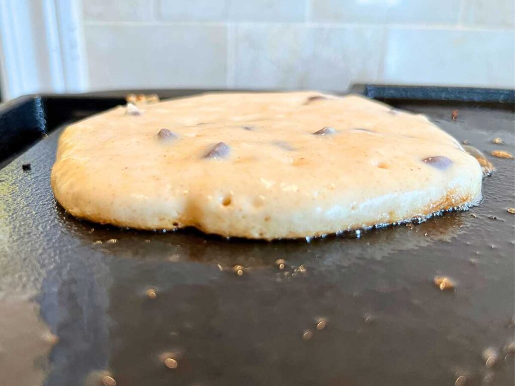 The side view of a pancake being cooked on a griddle.