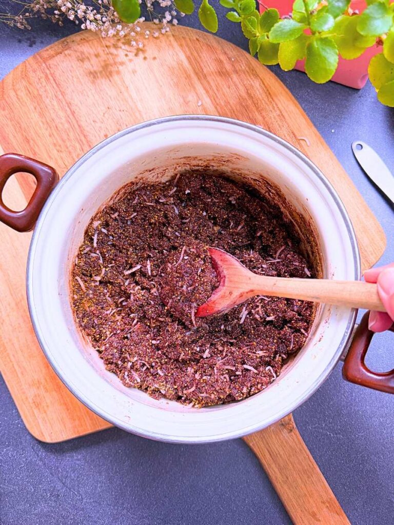A white sauce pot with a chocolate, graham cracker, and coconut mixture.