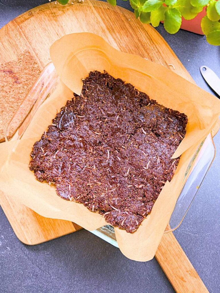 A chocolate and coconut base pressed out into a lined glass pan.