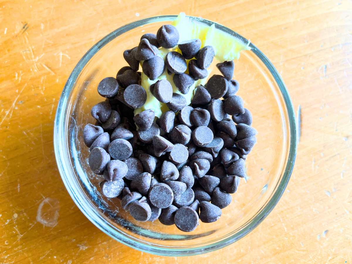 A small glass bowl of chocolate chips and butter.