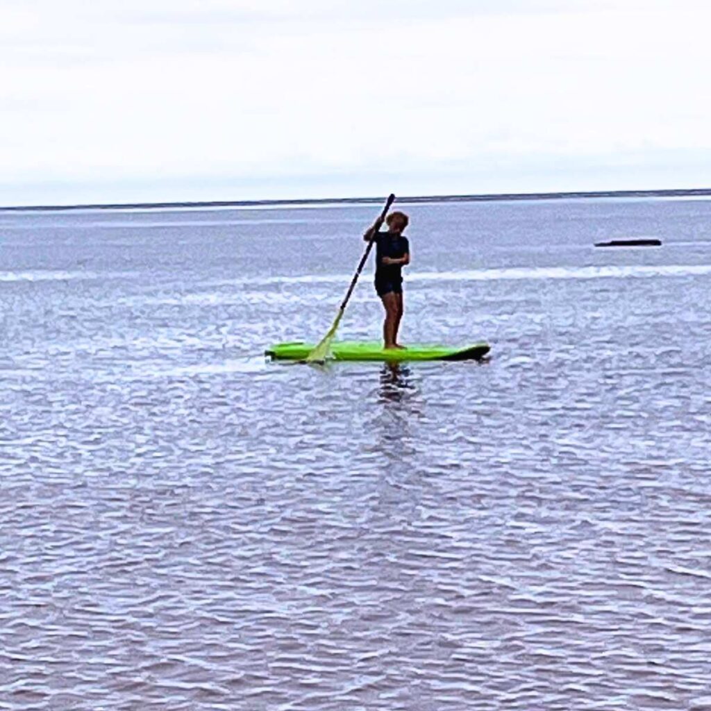 A little girl paddle boarding in the ocean