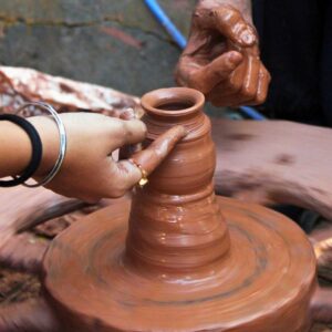 Two people making pottery on a wheel.