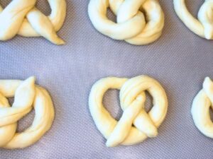dough pretzels on a baking sheet with a mat.