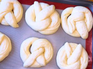 Risen pretzel dough on a baking sheet with a mat.