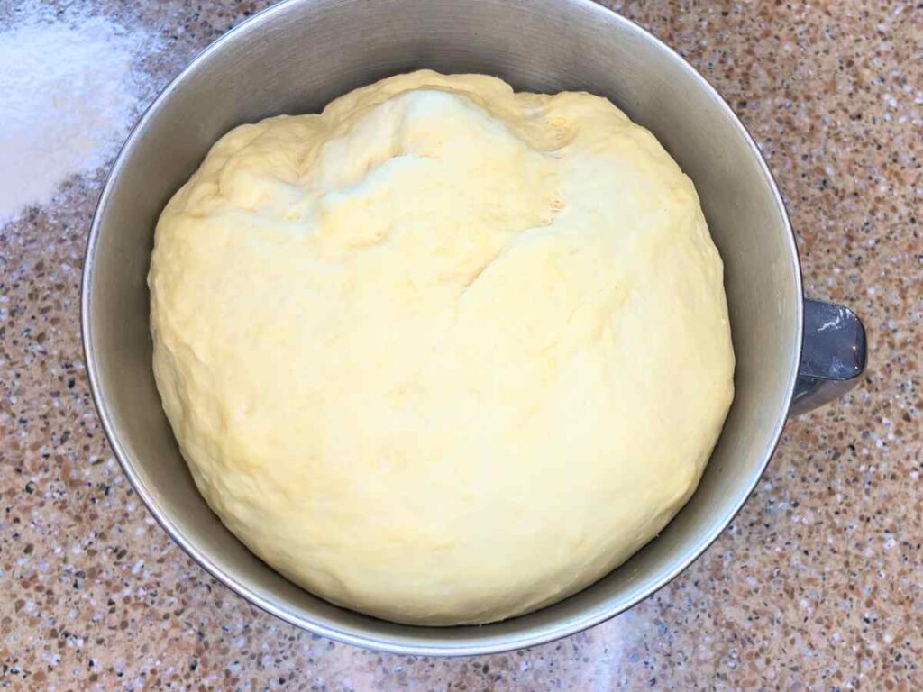 Risen dough in the bowl of a stand mixer.