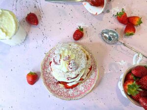 An overhead look at a strawberry shortcake. There are whole strawberries around.