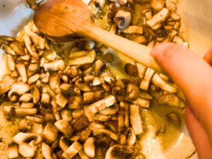 Sliced mushrooms frying in a pot.