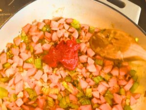 Vegetables and tomato paste cooking in a large pot.