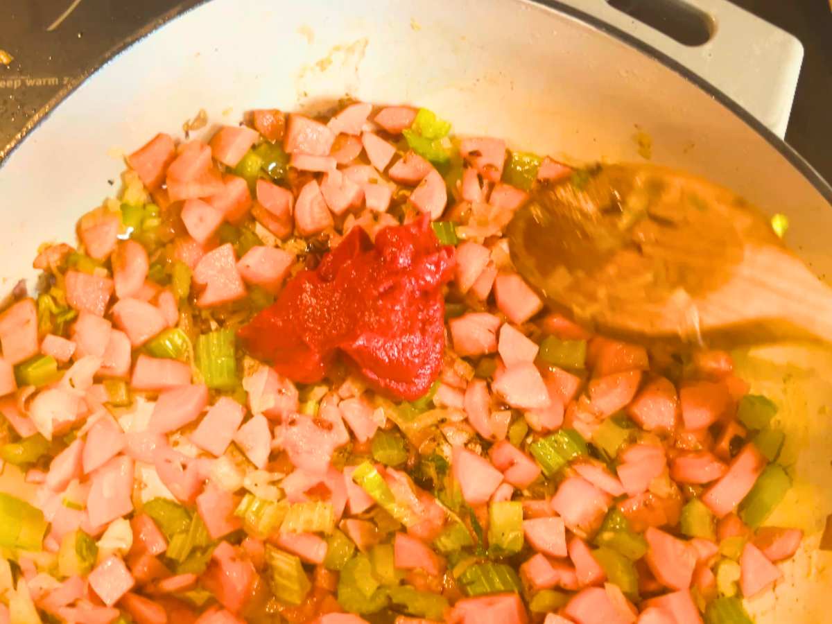 Vegetables and tomato paste cooking in a large pot.