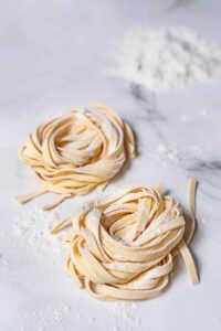 Fresh pasta noodles formed into two nest shapes.