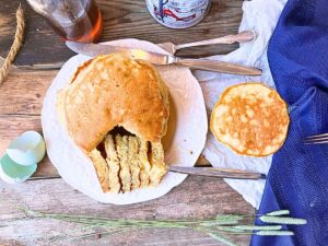 A stack of pancakes with a wedge cut out. There is one pancake off to the side.