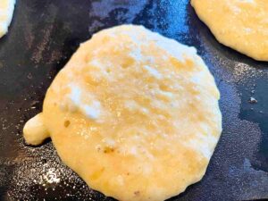 Pancake batter cooking on a griddle.