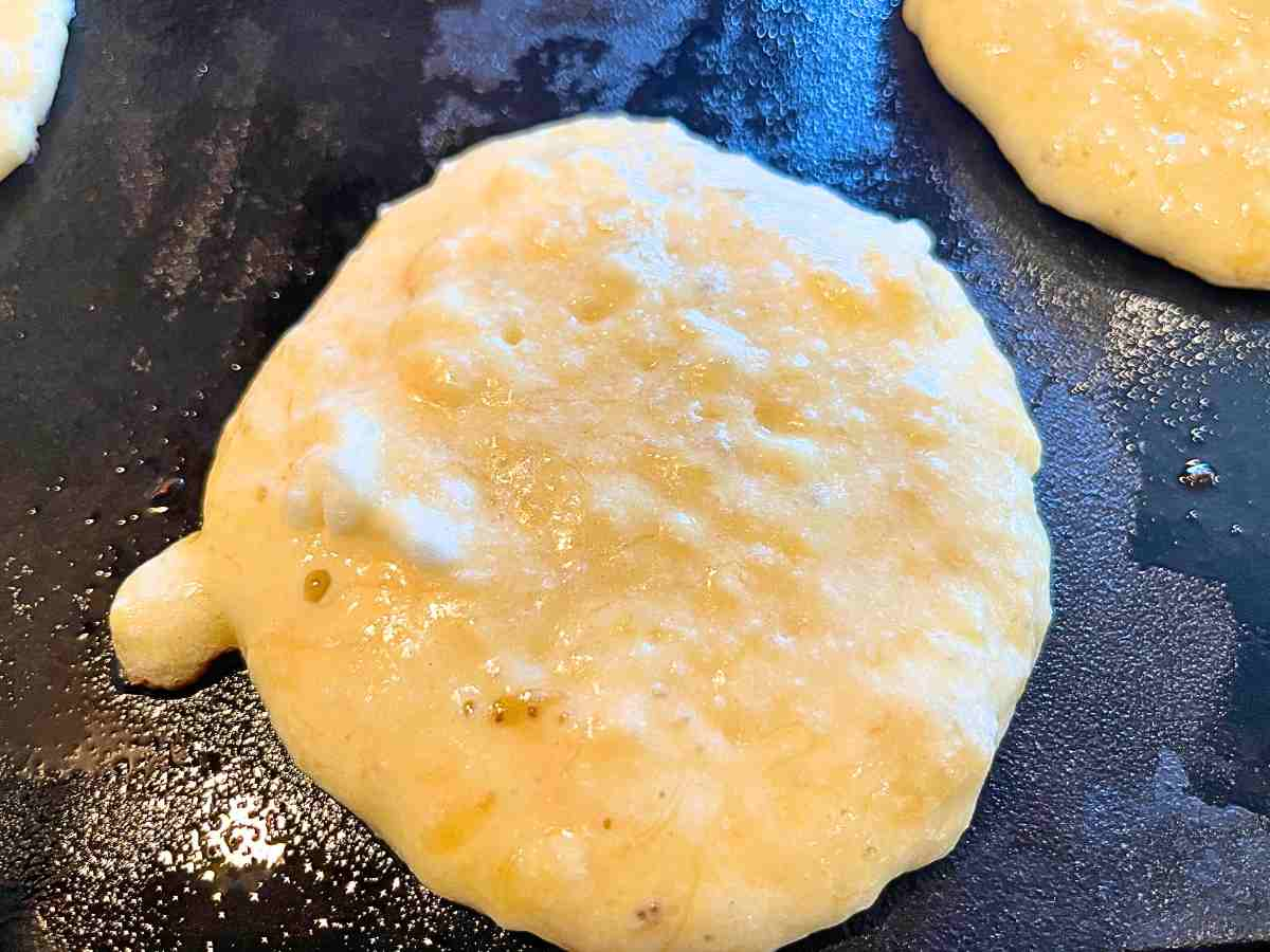 Pancake batter cooking on a griddle.