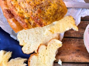 An overhead look at a sliced cheese bread loaf. There are slices in front.