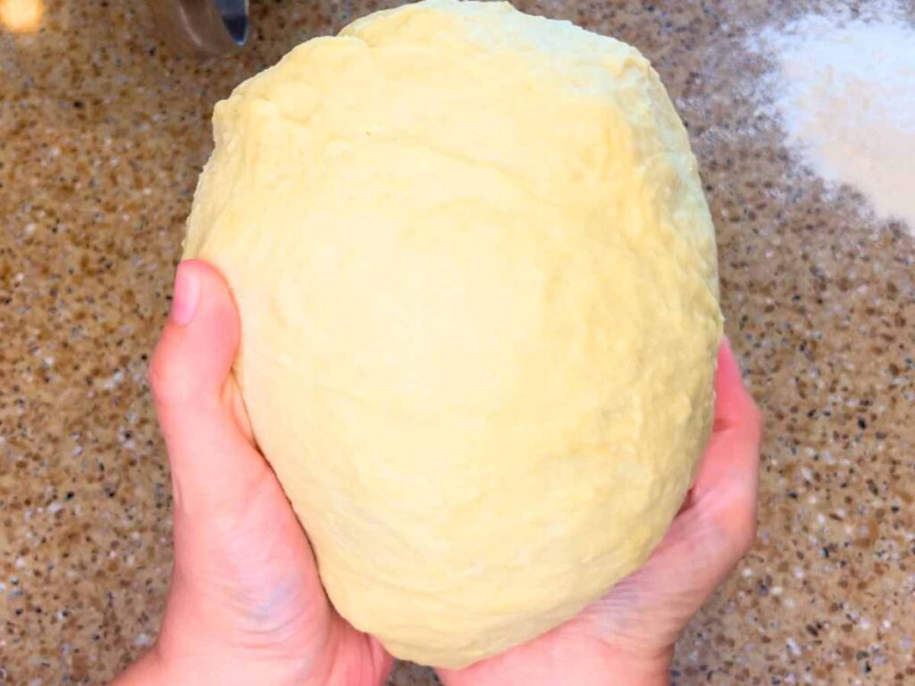 A woman holding a boule of dough.