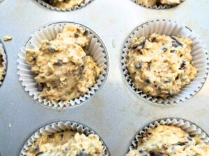 Muffin batter in a muffin tray lined with paper cups.