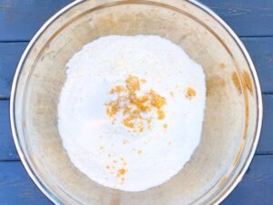 A metal bowl with flour and brown sugar inside.