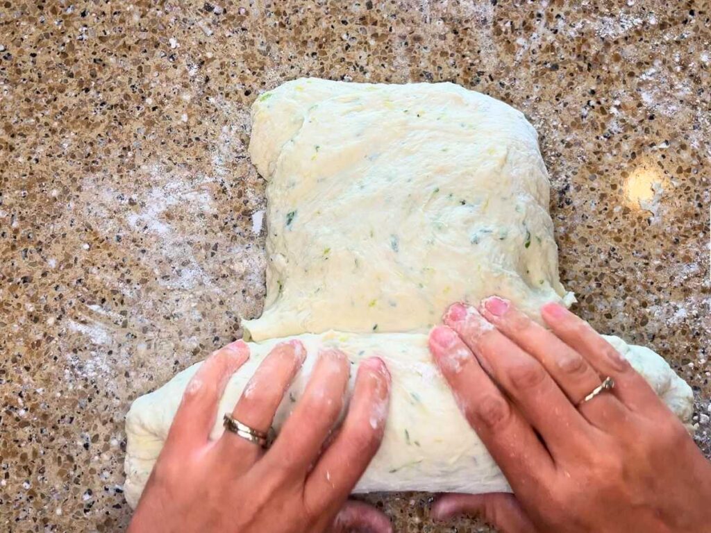 A woman rolling vegetable bread dough.