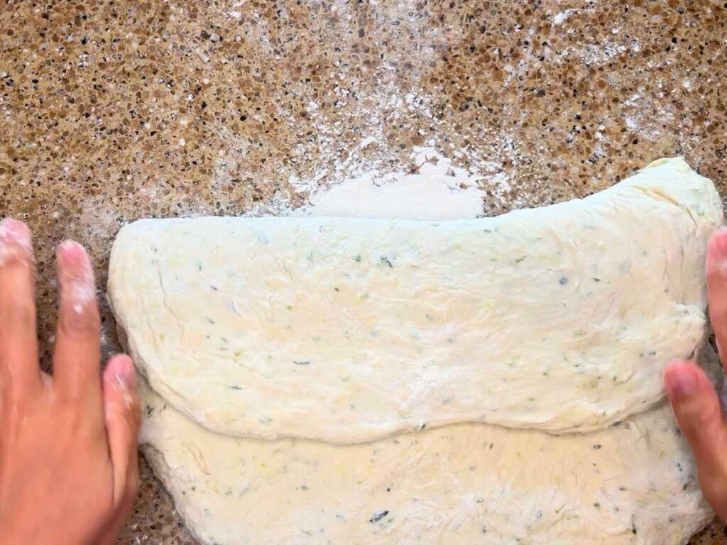 A woman shaping a vegetable bread dough to a loaf.