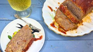 An over head view of a sliced meatloaf. There is a plate with a slice on it in the front.