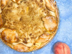 A baked pie with a peach sitting beside.