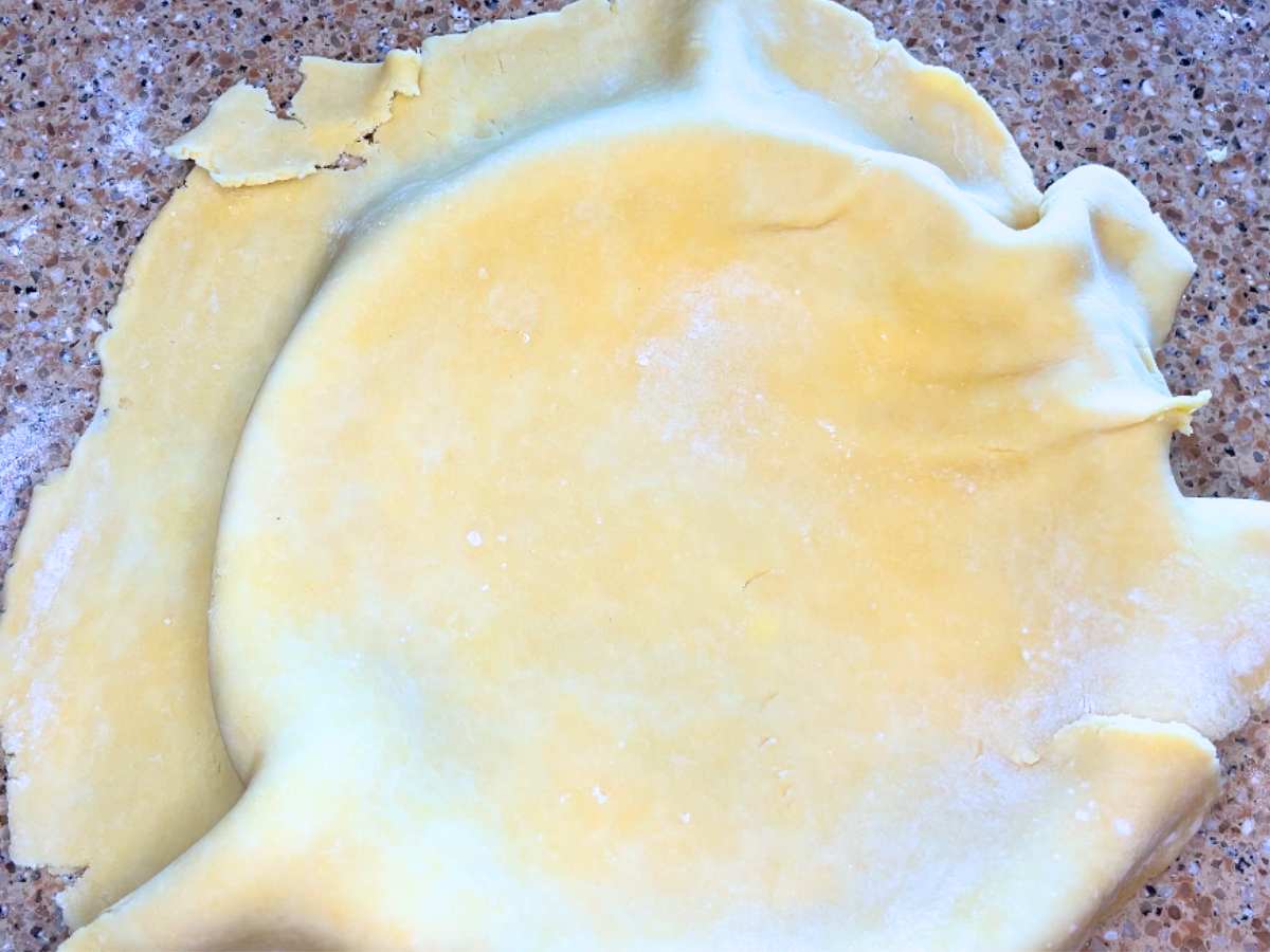 There is pie dough over top of a pie plate.